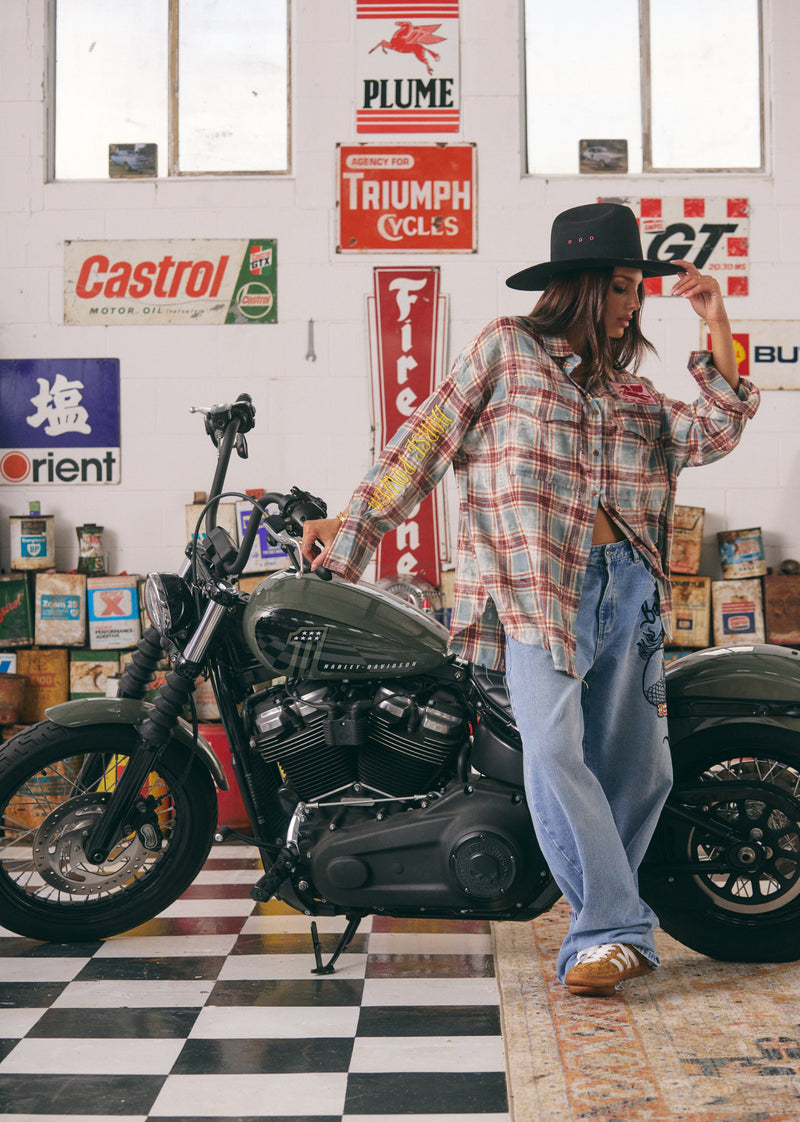 Person standing next to a motorcycle in a garage with vintage posters on the wall.