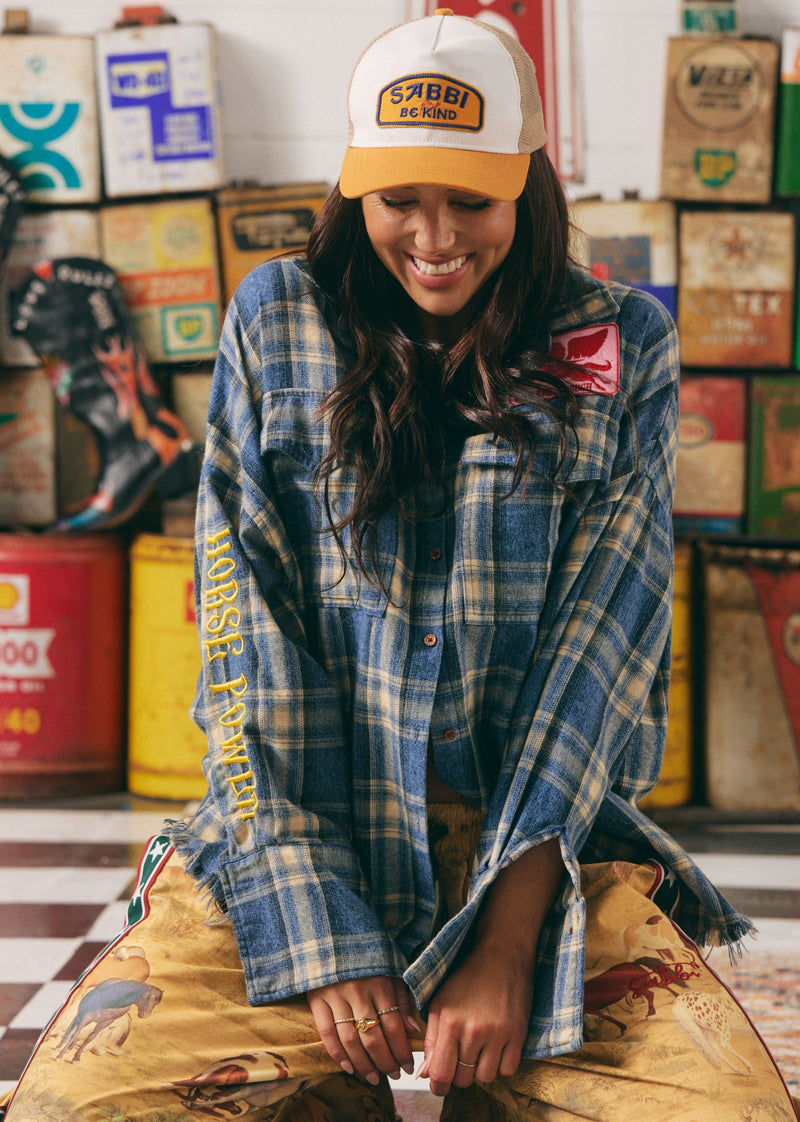 Person wearing a plaid shirt and cap in a room with vintage items
