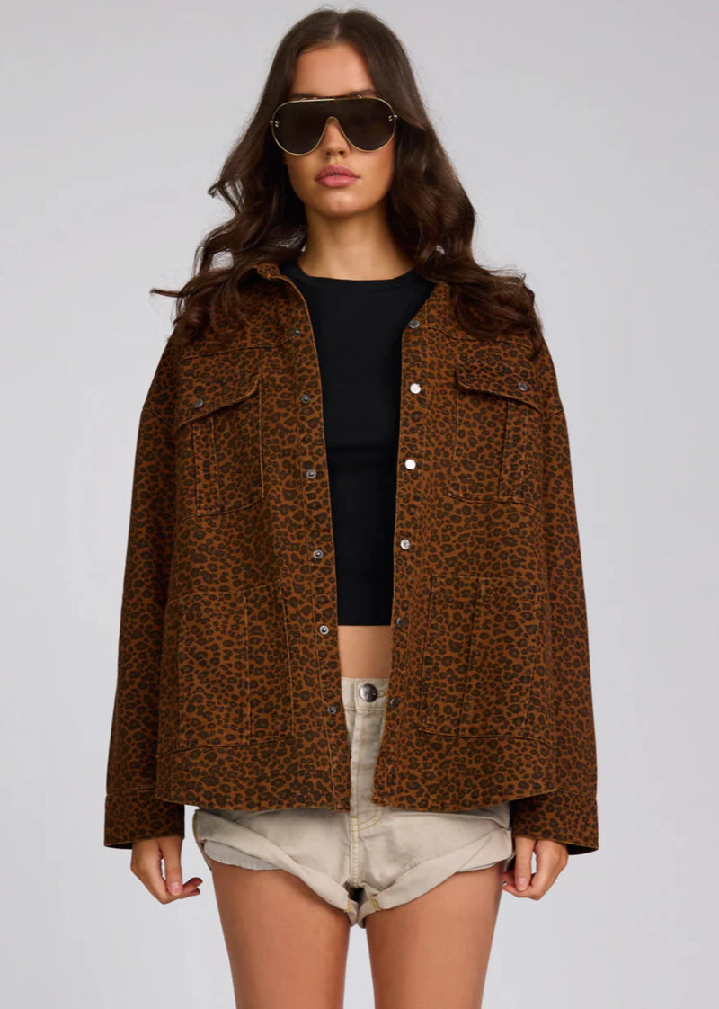 Woman wearing a brown leopard print jacket on a plain background