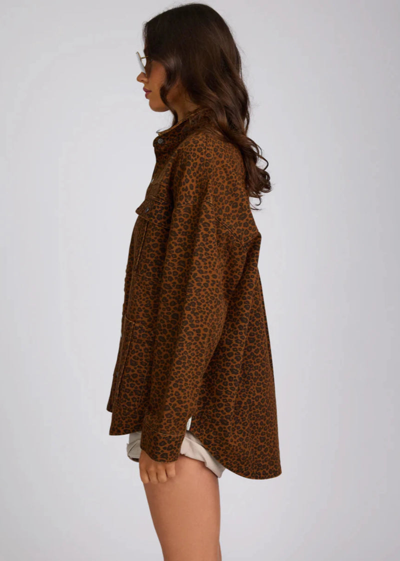 Woman wearing a brown leopard print shirt against a white background